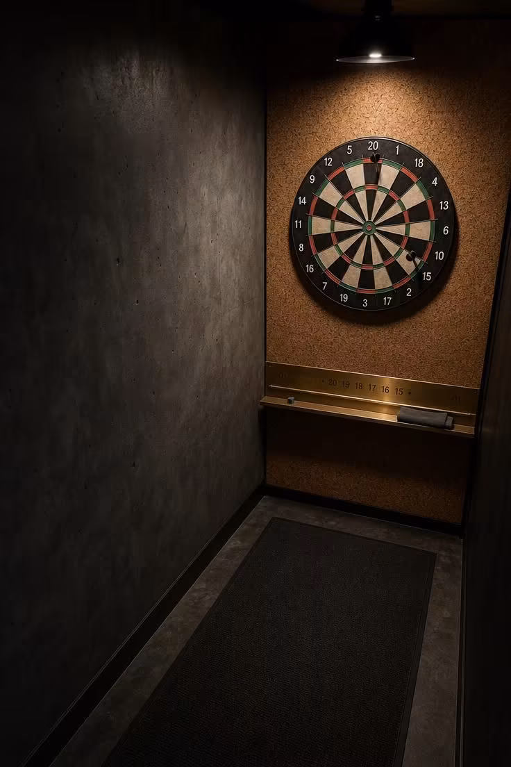 13 Stylish Game Room Ideas for Adults to Lounge and Play 7 Overhead view of a dart alley with a cork wall, dartboard, and brass score rail.