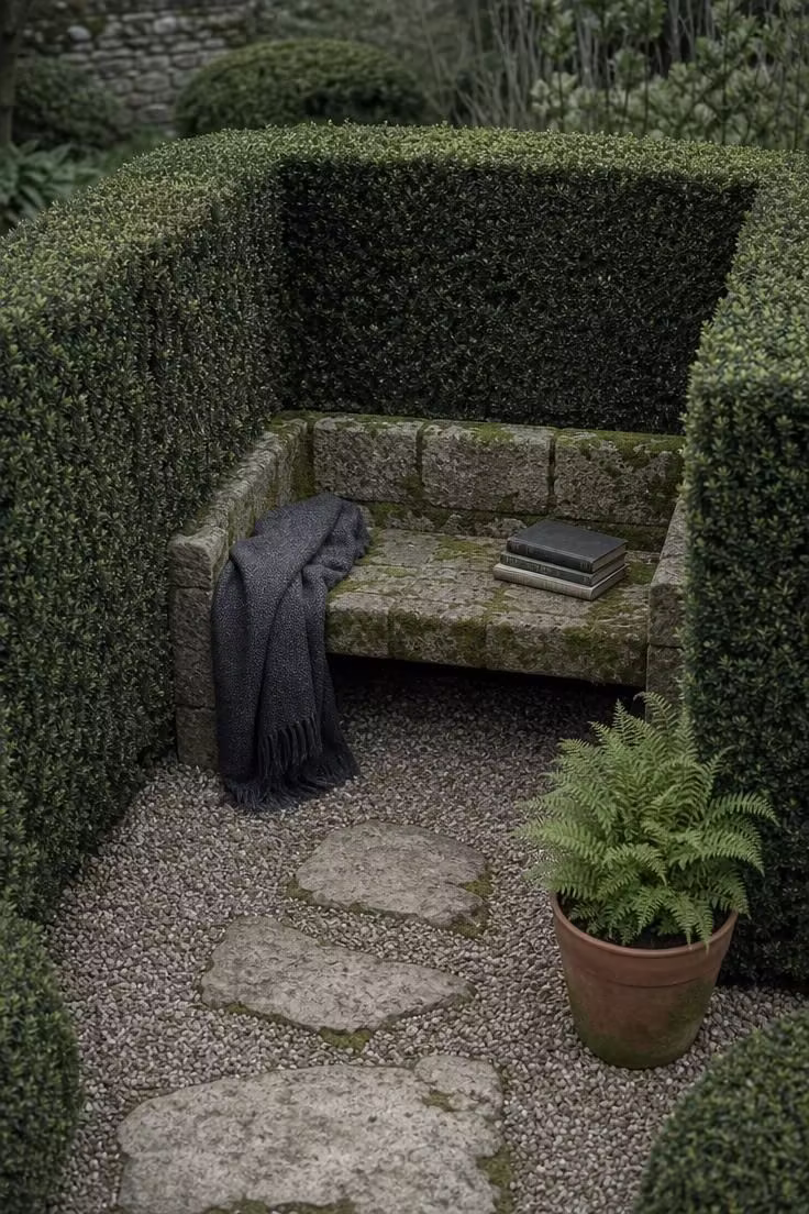 13 Lovely Garden Reading Nook Ideas for Quiet Moments 2 Moss-covered stone bench inside a boxwood hedge alcove on an overcast morning