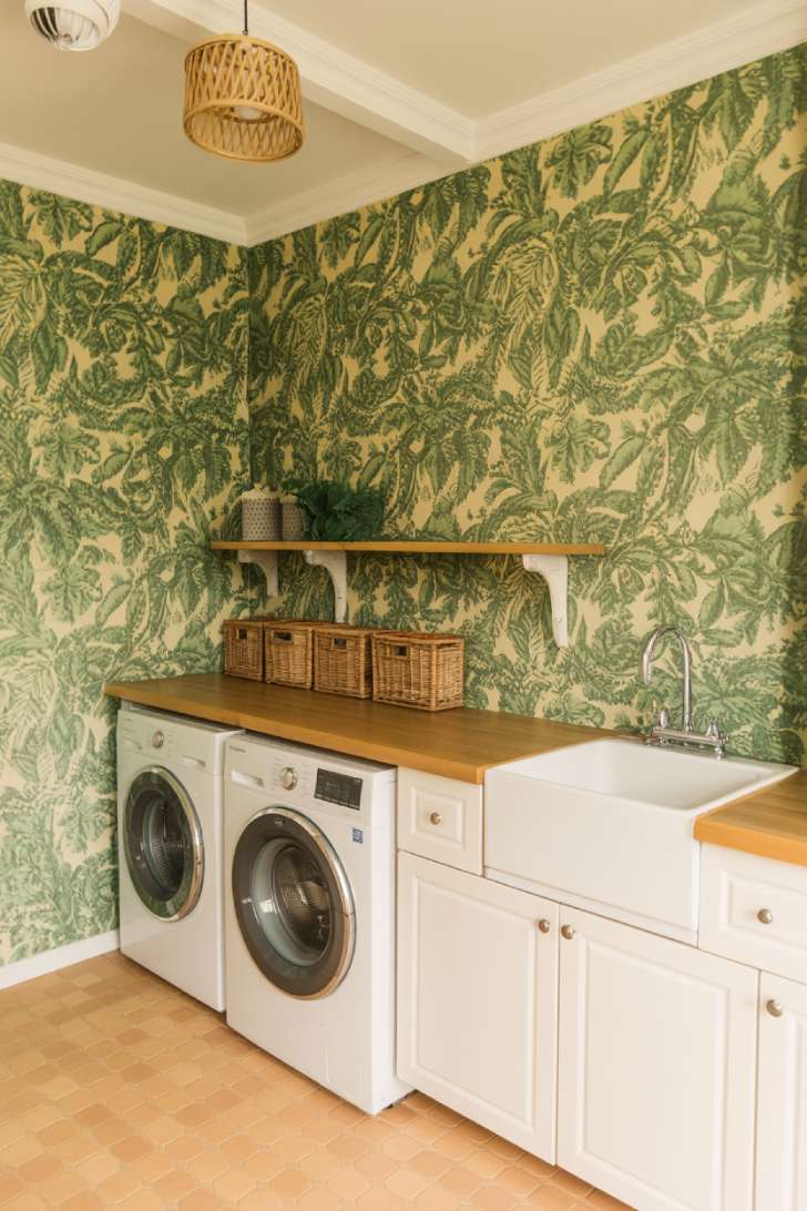 13 Brilliant Green Laundry Room Ideas for a Stylish Space 7 Botanical green wallpaper laundry room with white cabinets, terracotta tile floor, and rattan light