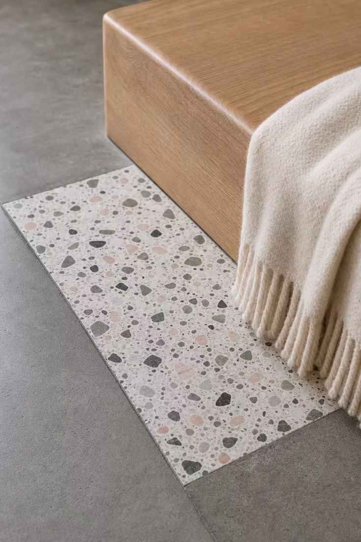 13 Charming Hallway Reading Nook Ideas for Small Homes 12 A close-up detail of terrazzo tile meeting a low oak reading platform with a folded cream wool throw in cool overcast light.