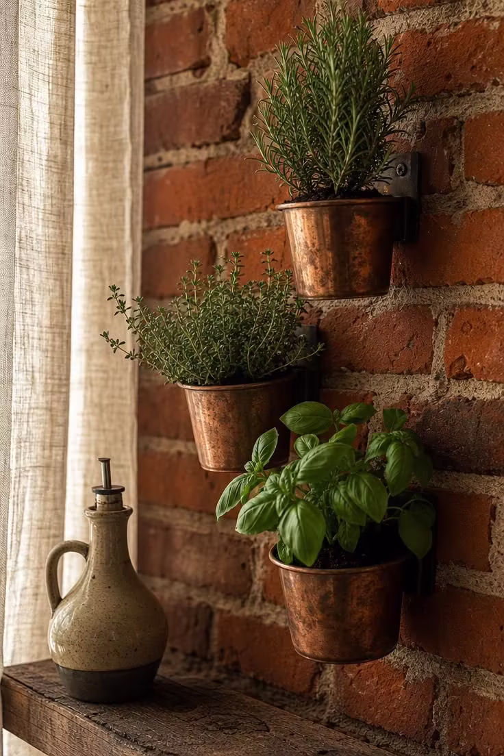 Copper herb planters mounted on an exposed brick accent wall in a soft-lit industrial boho kitchen