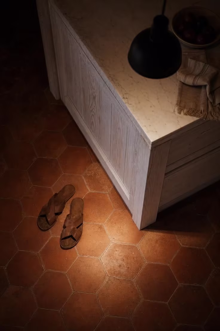 Terracotta hexagon floor tiles meeting a whitewashed wood island base in a moody industrial boho kitchen