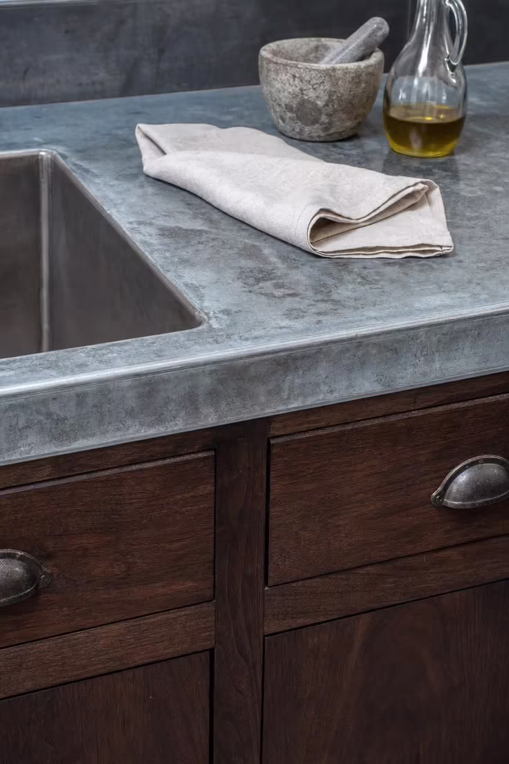 15 Bold Industrial Kitchen Ideas That Feel Lived In 12 Zinc-wrapped countertop with mottled patina over dark walnut base cabinets in a bright industrial kitchen