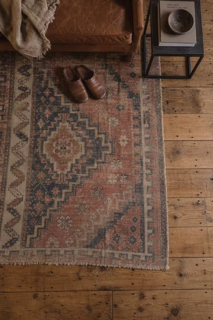 17 Striking Industrial Living Room Ideas With Raw Charm 12 Overhead view of a faded vintage kilim rug layered over wide-plank reclaimed hickory flooring in an industrial living room.