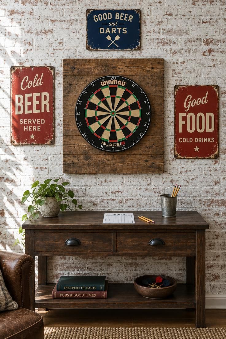 13 Warm Industrial Man Cave Ideas for Your Hangout 10 A dartboard on a reclaimed wood backer board flanked by vintage enamel signs in faded red, cream, and navy on a whitewashed brick wall above a low console.