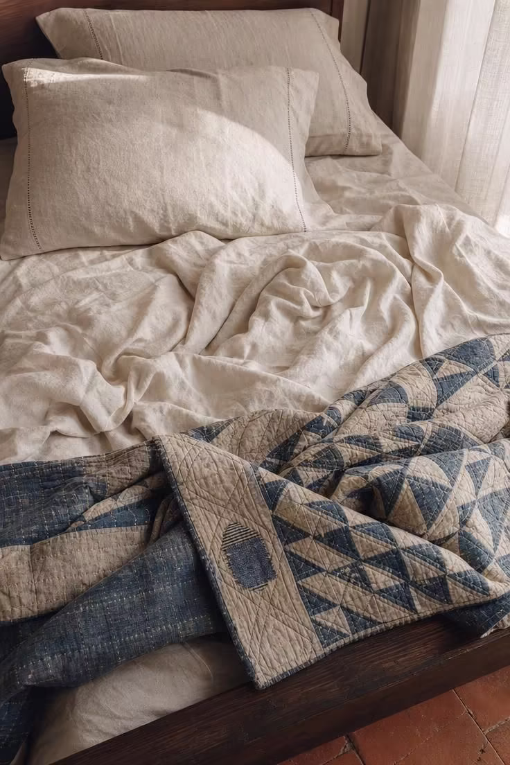 11 Breezy Italian Summer Bedroom Ideas for Lazy Afternoons 2 Crumpled oyster cream linen bedding layered with an antique indigo quilt in a soft Italian summer bedroom.