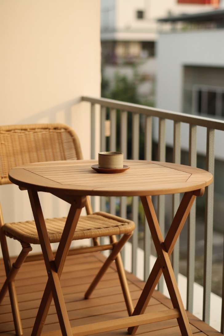 11 Dreamy Japandi Balcony Ideas to Create Your Zen Space 5 Small round teak folding table with ceramic cup on a minimalist japandi balcony