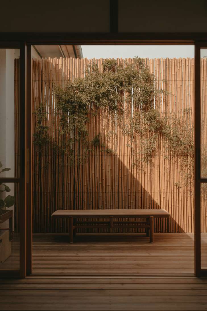 11 Dreamy Japandi Balcony Ideas to Create Your Zen Space 8 Natural bamboo privacy screen with trailing jasmine on a teak japandi balcony