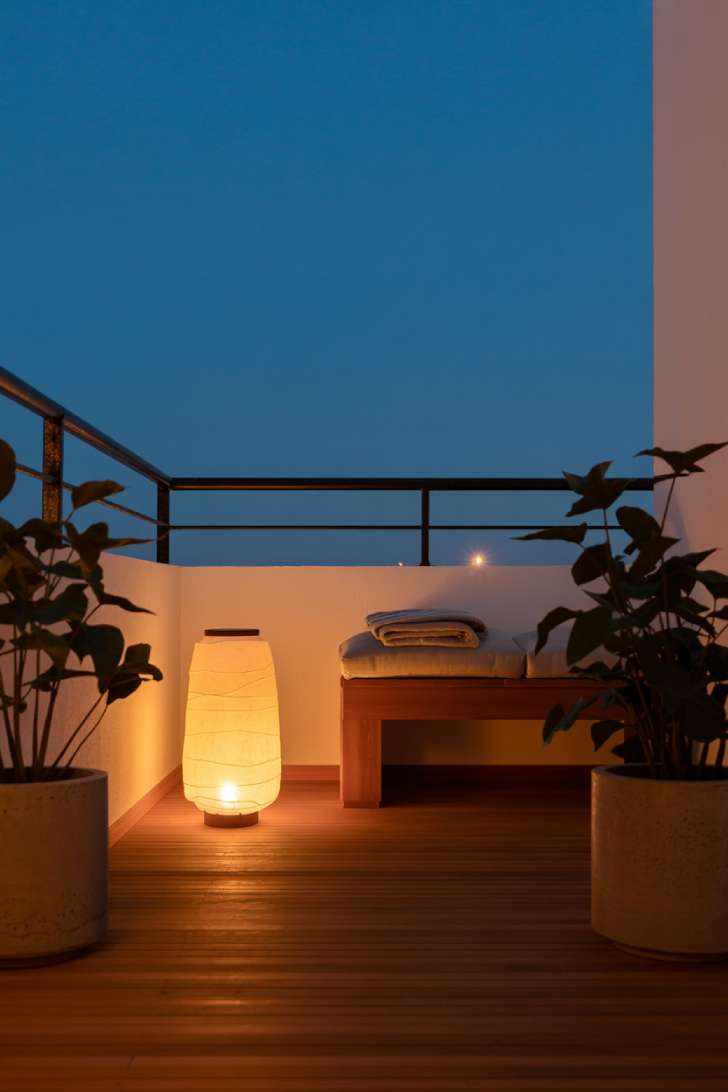 11 Dreamy Japandi Balcony Ideas to Create Your Zen Space 9 Ceramic floor lantern casting warm amber light on a japandi balcony at dusk