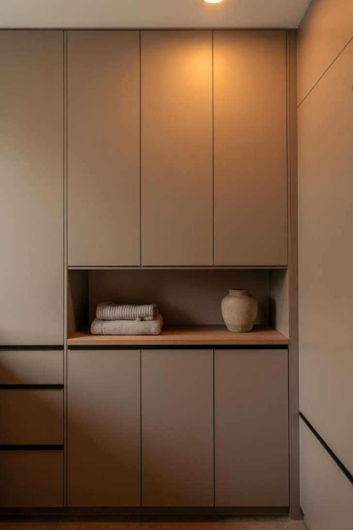 Floor-to-ceiling flat-panel taupe cabinets with hidden push-to-open hardware in a minimalist japandi laundry room.