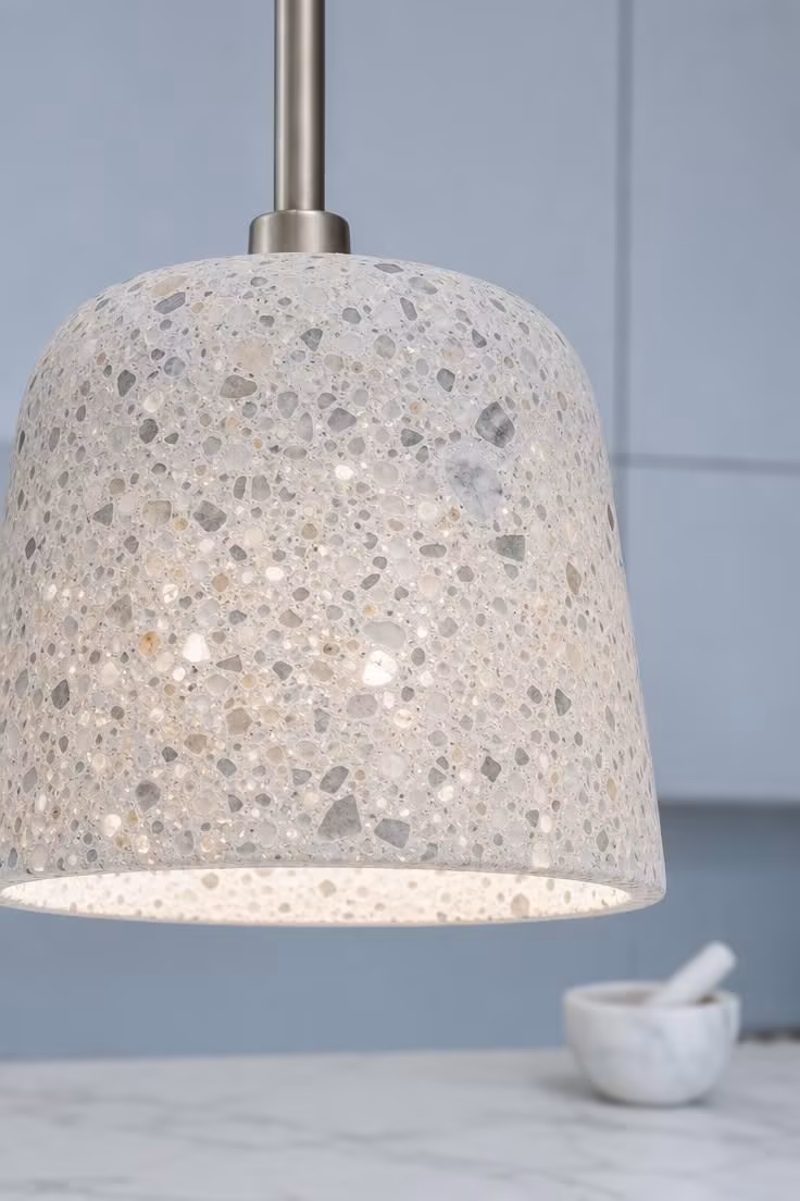 A terrazzo composite pendant with satin nickel stem shows speckled stone chips glowing from within.