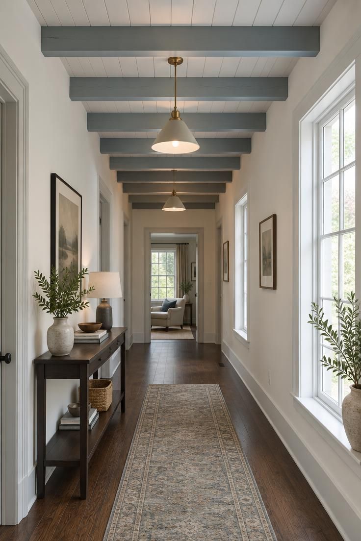 13 Clever Large Hallway Ideas to Make Yours Feel Like a Room 12 An overhead view along a hallway ceiling with painted timber beams running along the long axis, pale ceiling boards between them, and pendants grazing light across the beam edges above a dark oak floor.
