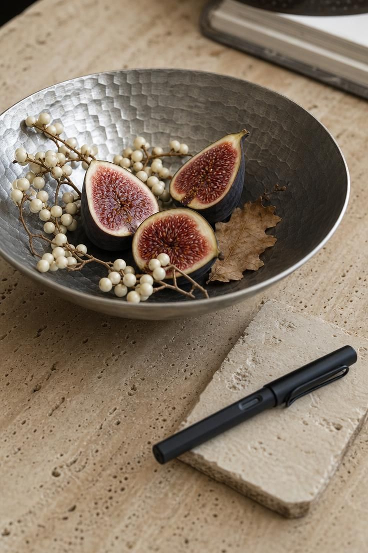 10 Muted Palettes for Luxury Fall Decor You'll Love 5 Hammered pewter bowl with fig halves and ivory tallow berries on a travertine desk beside a matte black fountain pen on a small coaster.