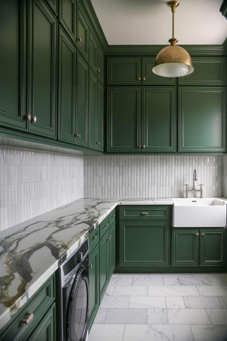 13 Luxury Laundry Room Ideas That Make Chores Enjoyable 9 Deep forest green matte cabinetry with Statuario marble countertop and brass pendant in a luxury laundry room