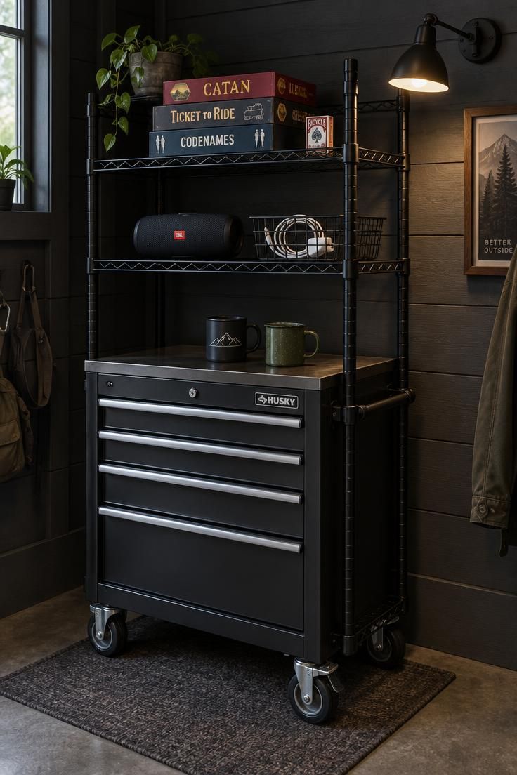 13 Cozy Man Cave Shed Ideas for a Quiet Backyard Escape 8 A black wire shelf above a rolling metal tool cart in a charcoal shed corner, holding board games, a speaker, and two mugs under a side-mounted wall sconce.