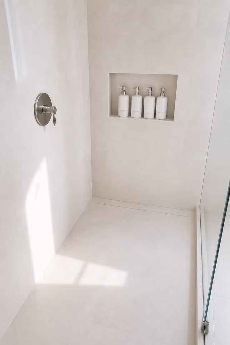 9 Low-Lift Updates That Make Master Bathrooms With Walk In Showers Feel Like a Spa Retreat 5 A bright walk in shower interior with four matching white ceramic pump bottles arranged in a recessed niche, frameless glass and pale ivory large format tile throughout