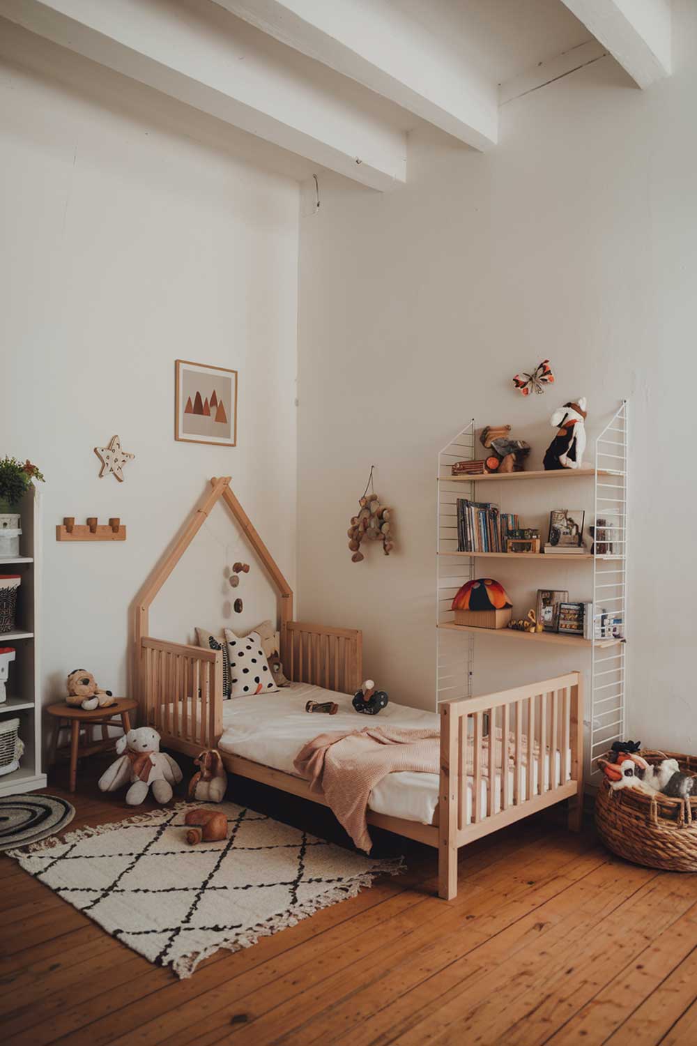 A cozy minimalist kids bedroom with a wooden bed, a few toys, and a bookshelf. The room has white walls and a wooden floor. There is a small rug near the bed. The room has a warm and inviting atmosphere.