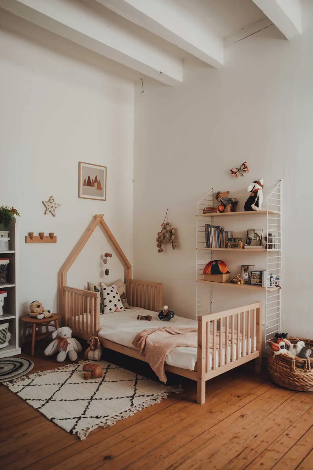 29 Minimalist Kids Bedroom Ideas: Simple Yet Playful Designs 2 A cozy minimalist kids bedroom with a wooden bed, a few toys, and a bookshelf. The room has white walls and a wooden floor. There is a small rug near the bed. The room has a warm and inviting atmosphere.