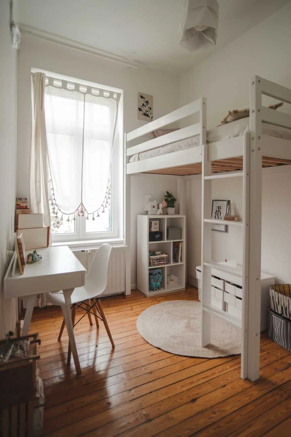 29 Minimalist Kids Bedroom Ideas: Simple Yet Playful Designs 3 A cozy minimalist kids bedroom with a white loft bed, a white desk with a chair, and a small bookshelf. There is a window with a curtain near the bed. The floor is made of wooden planks. The room is bright.