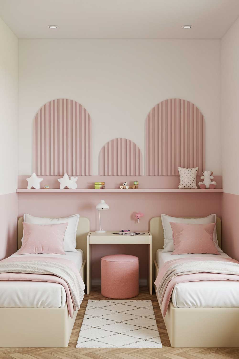 A minimalist kids bedroom design with a shared room for two girls. The room has two single beds with white sheets and pink pillows. There's a small desk between the beds with a desk lamp. On the wall above the bed is a decorative pink and white striped pattern. Below the decor is a shelf with a few toys. The floor is covered with a white rug. The room has a few pink and white decor items. The room has a wooden floor.