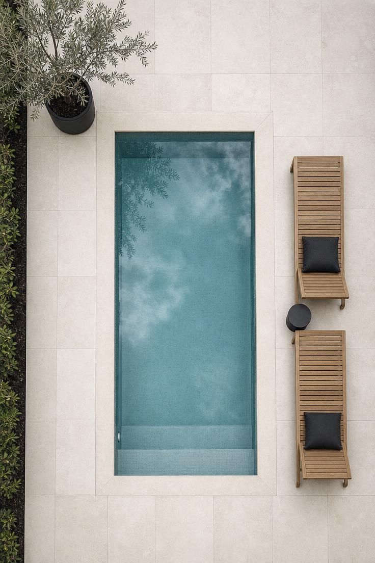 17 Sleek Modern Backyard Landscaping Plans Worth Copying 7 Overhead view of a rectangular plunge pool with flush limestone coping and teak loungers on a pale limestone deck in soft diffused light.