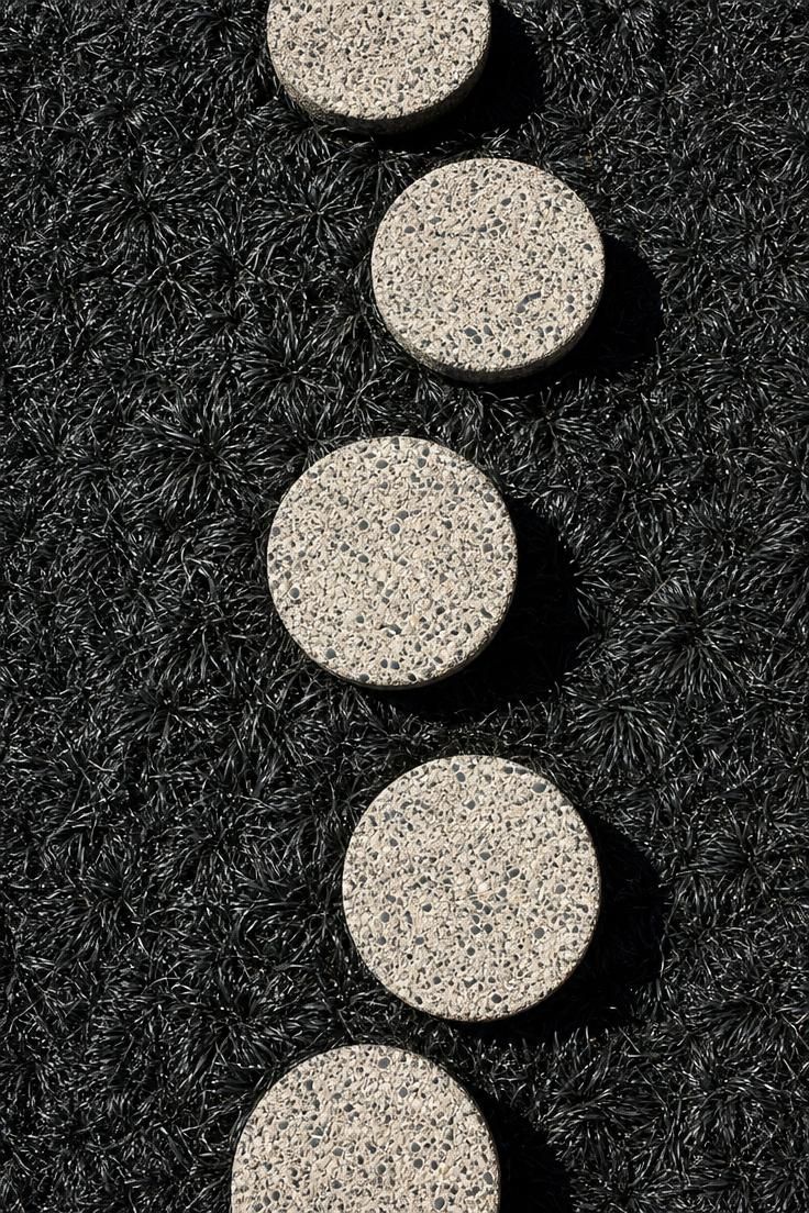 17 Sleek Modern Backyard Landscaping Plans Worth Copying 11 Overhead view of circular aggregate concrete stepping pads set in black mondo grass with high contrast midday shadows.