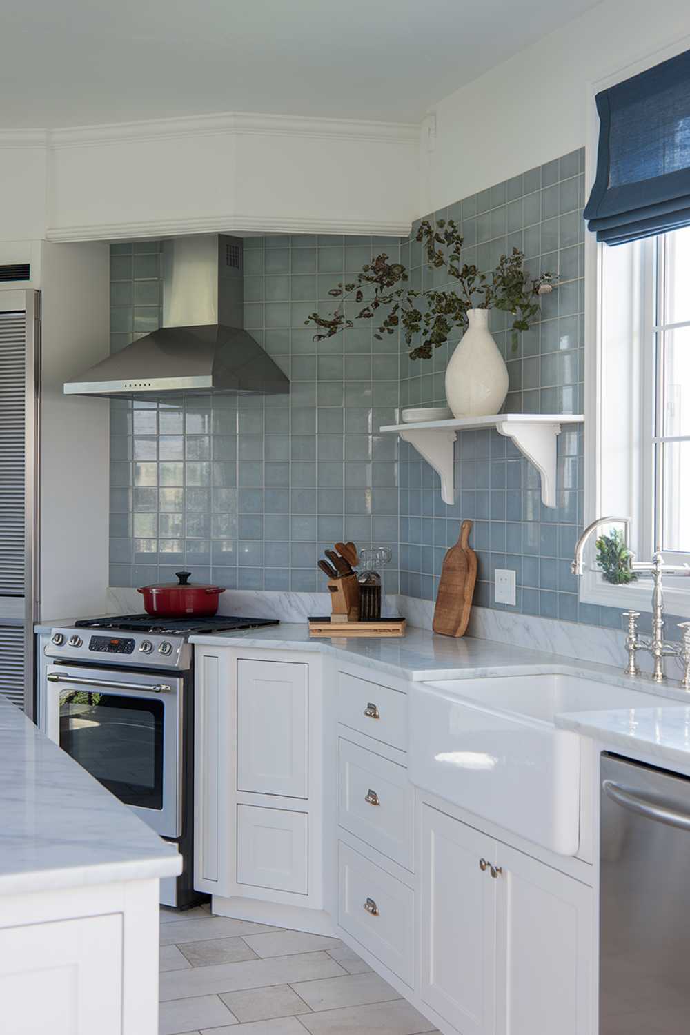 Modern coastal kitchen featuring blue tile backsplash, white cabinets, and farmhouse sink