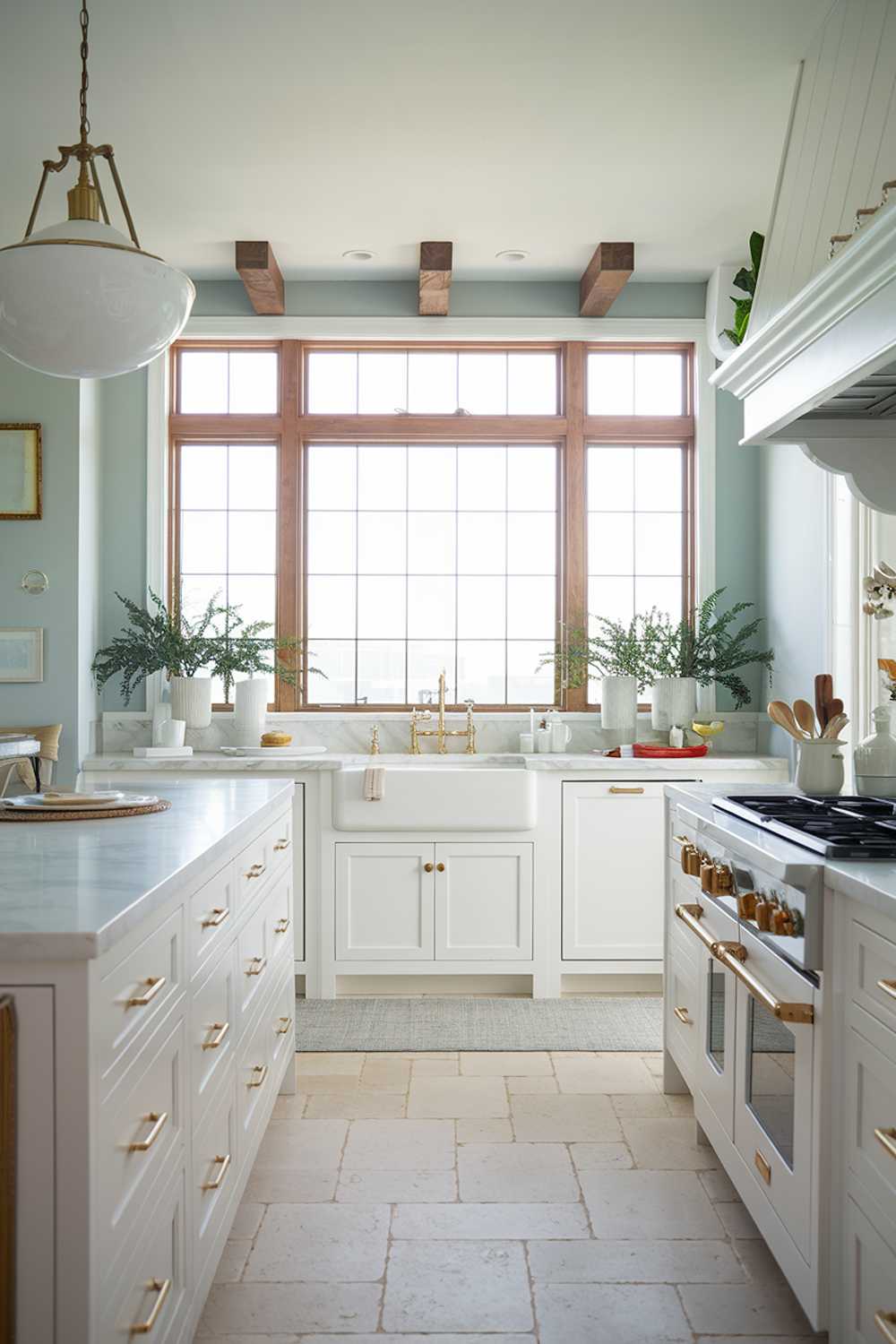 Modern coastal kitchen with gold fixtures, marble countertops, and wooden beam accents