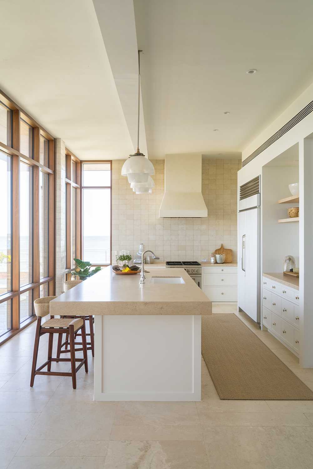 Modern coastal kitchen with beige and white color scheme, island with barstools, and wooden frames