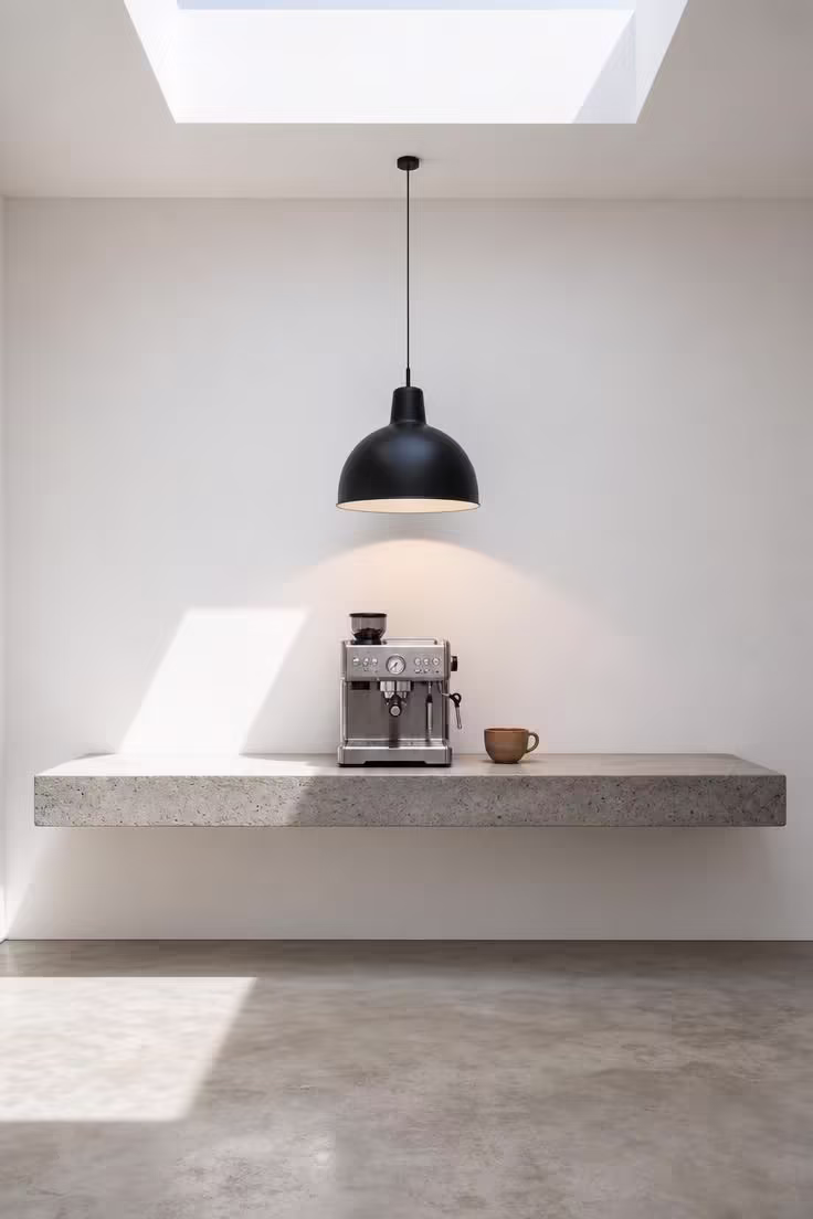 11 Modern Coffee Bar Ideas That Make Mornings Feel Special 8 Floating concrete ledge coffee station with single pendant light and espresso machine in bright midday skylight