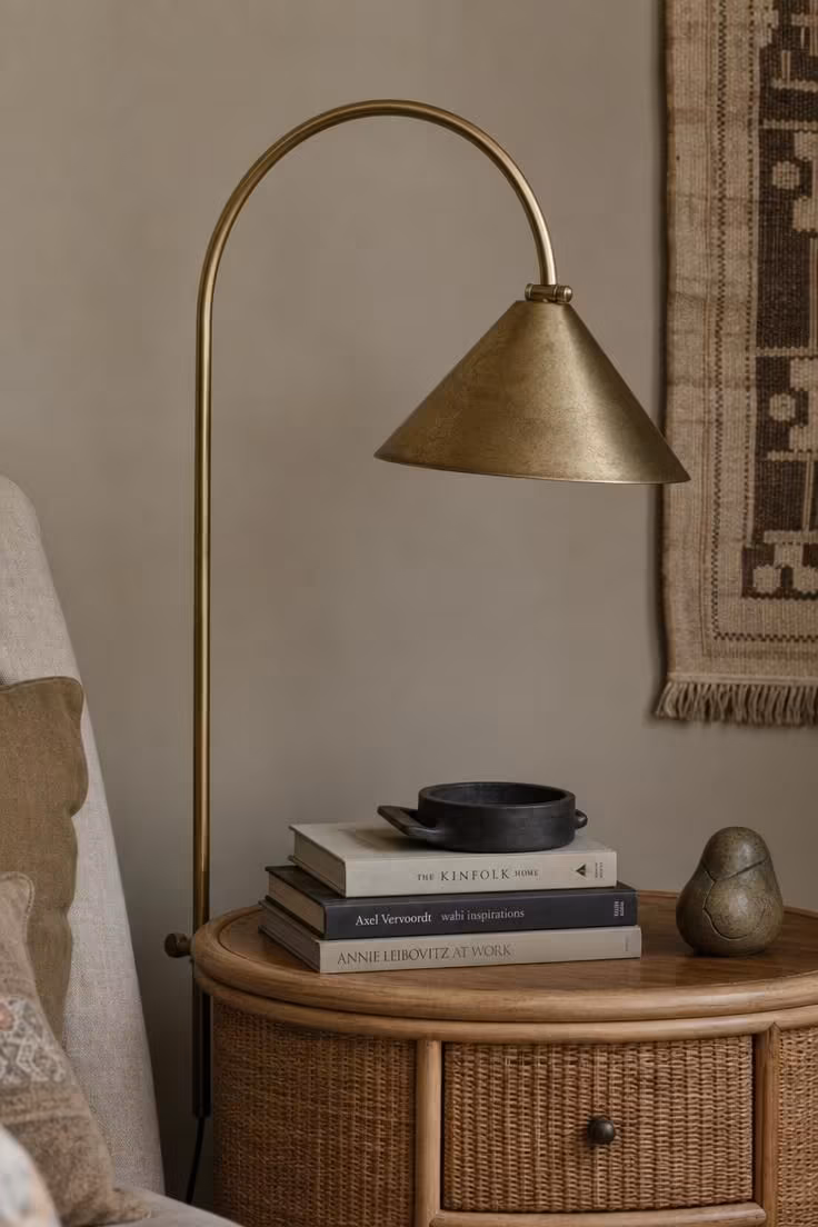 Brass arc floor lamp and rattan nightstand showing mixed metal accents in a modern eclectic bedroom.
