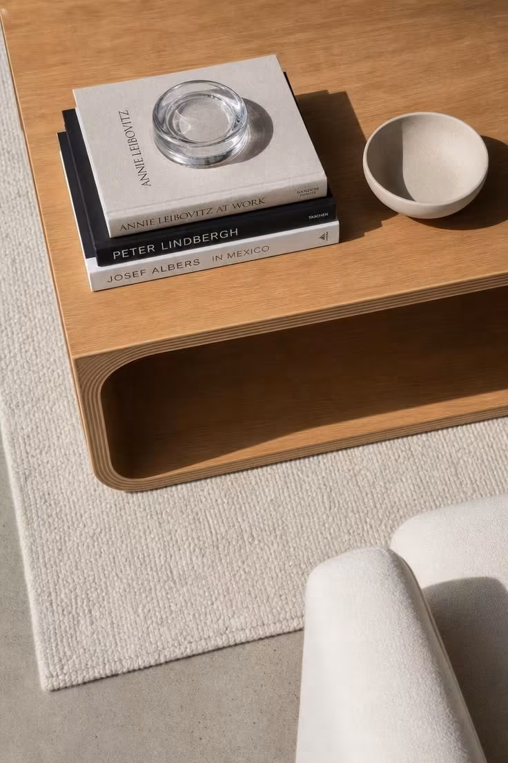 13 Modern Eclectic Living Room Ideas for Easy Sophistication 4 An overhead view of a low bentwood coffee table styled with a horizontal stack of art books, a glass catchall, and one ceramic bowl.