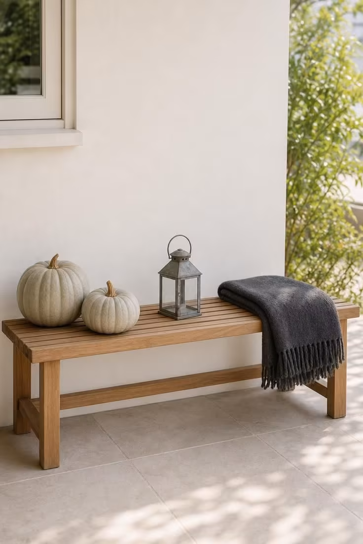 10 Modern Fall Porch Decor Ideas for a Cozy Welcome 5 A teak bench styled with two white Lumina pumpkins, a charcoal wool throw, and a zinc lantern.