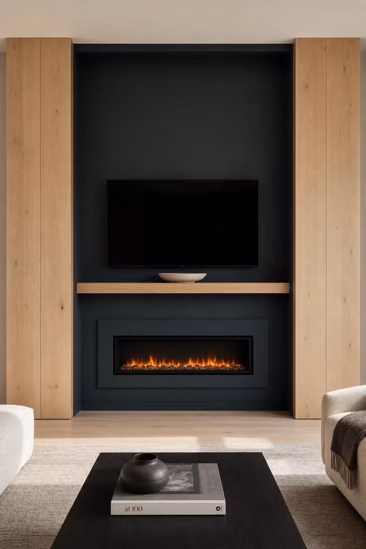 11 Modern Fireplace Ideas With TV for a Cozy Living Room 5 Twin white oak pillars flanking a deep blue-gray niche with a floating matte white electric fireplace and a TV on a suspended oak plinth in bright midday light.