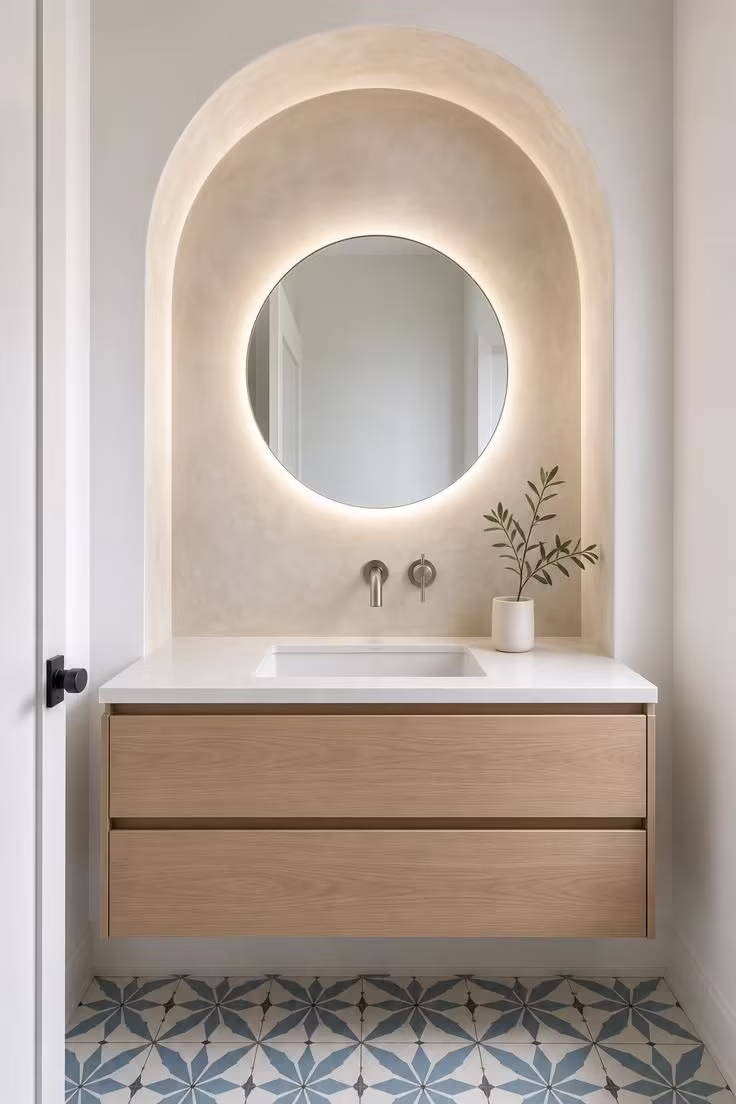 13 Modern Powder Room Ideas Packed With Personality 12 Polished plaster archway niche with a round backlit mirror above a floating oak vanity in a modern powder room