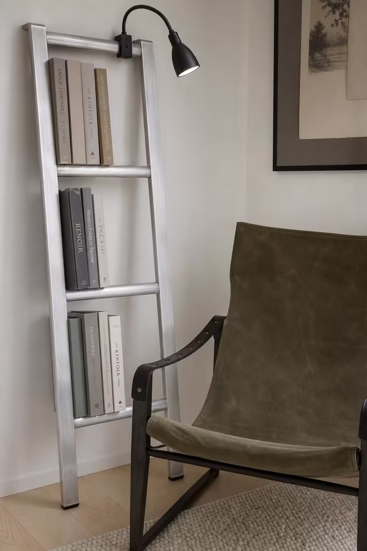 12 Modern Reading Nook Ideas for a Peaceful Retreat 4 Brushed aluminum ladder shelf with books beside an olive canvas sling chair in a modern reading nook