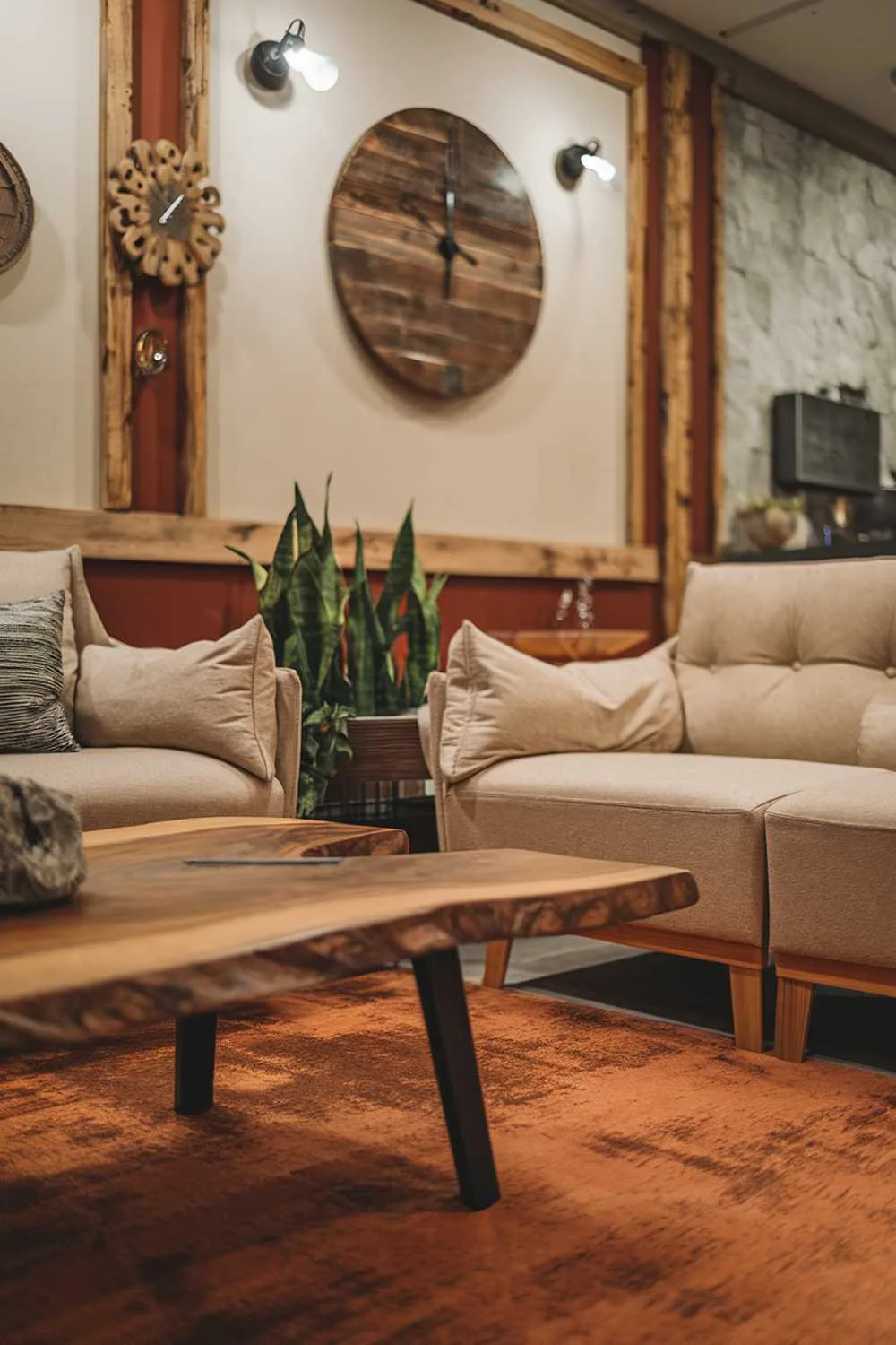 25 Modern Rustic Living Room Ideas: Comfort Meets Nature 21 A cozy modern rustic living room decor. There's a wooden coffee table with a burnt orange rug beneath it. The walls are adorned with a large, rustic wooden clock and a few decorative items. There are two beige sofas with wooden legs, and a green plant sits on one of the sofas. The room has a warm and inviting ambiance.