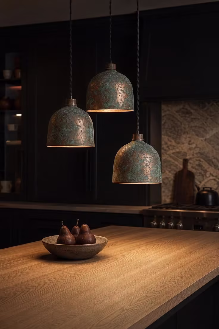 13 Modern Wabi Sabi Ideas That Feel Warm and Lived-In 10 Three oxidized copper pendant lamps with verdigris patina hanging above a rift-sawn white oak kitchen island