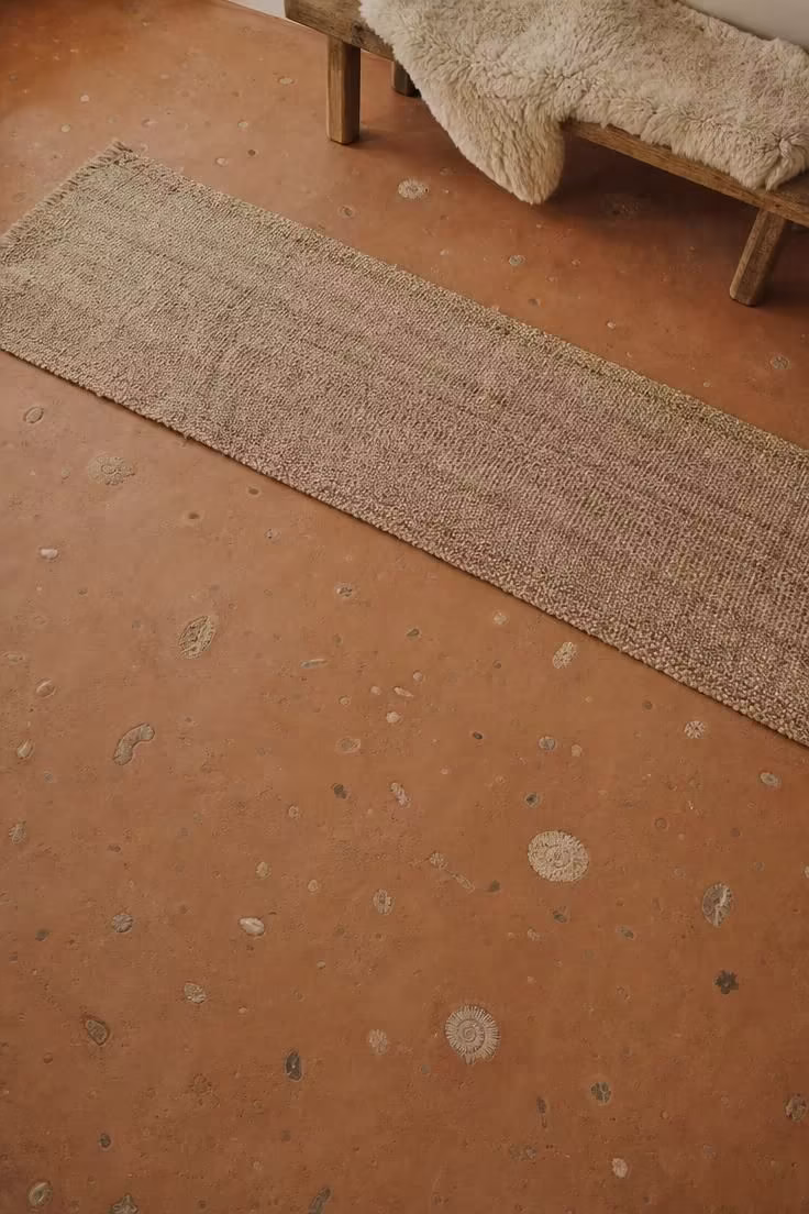 13 Modern Wabi Sabi Ideas That Feel Warm and Lived-In 11 Poured earthen clay floor with embedded fossil stone fragments and a jute runner in soft diffused light