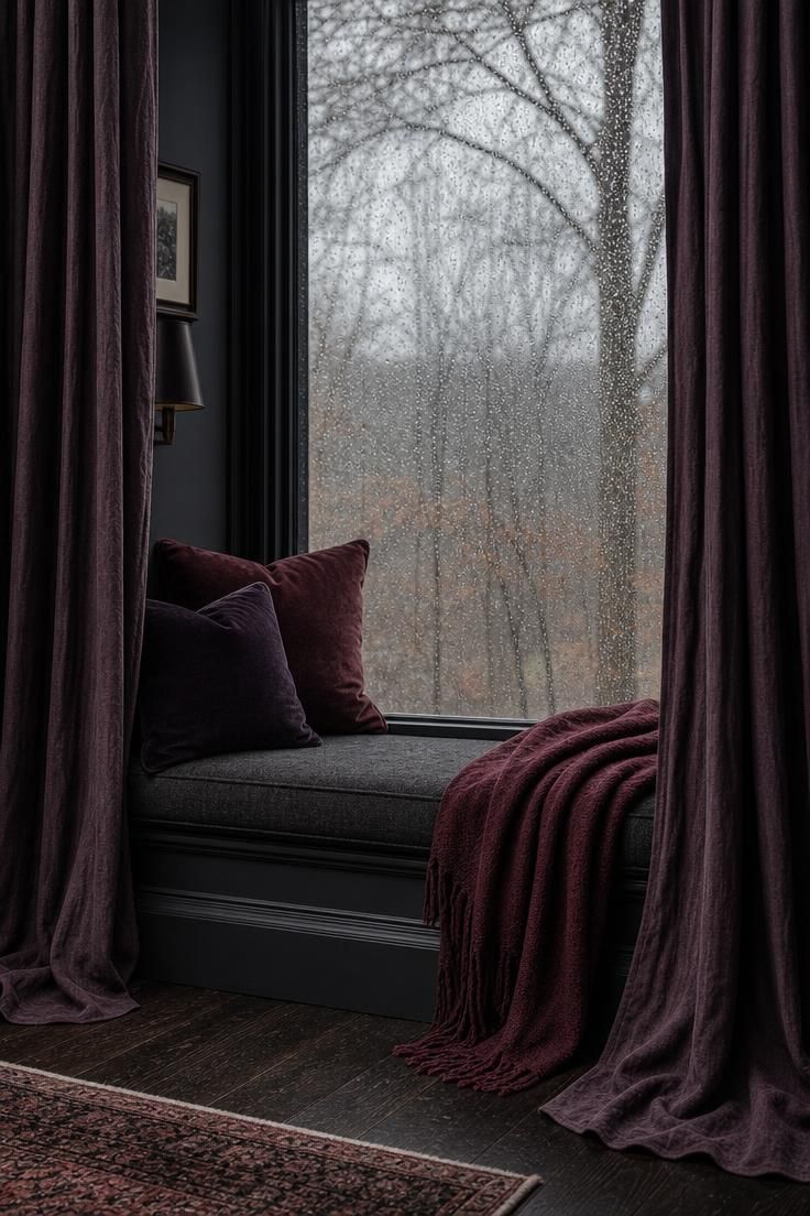 Aubergine linen curtains framing a window seat under gray, overcast light.