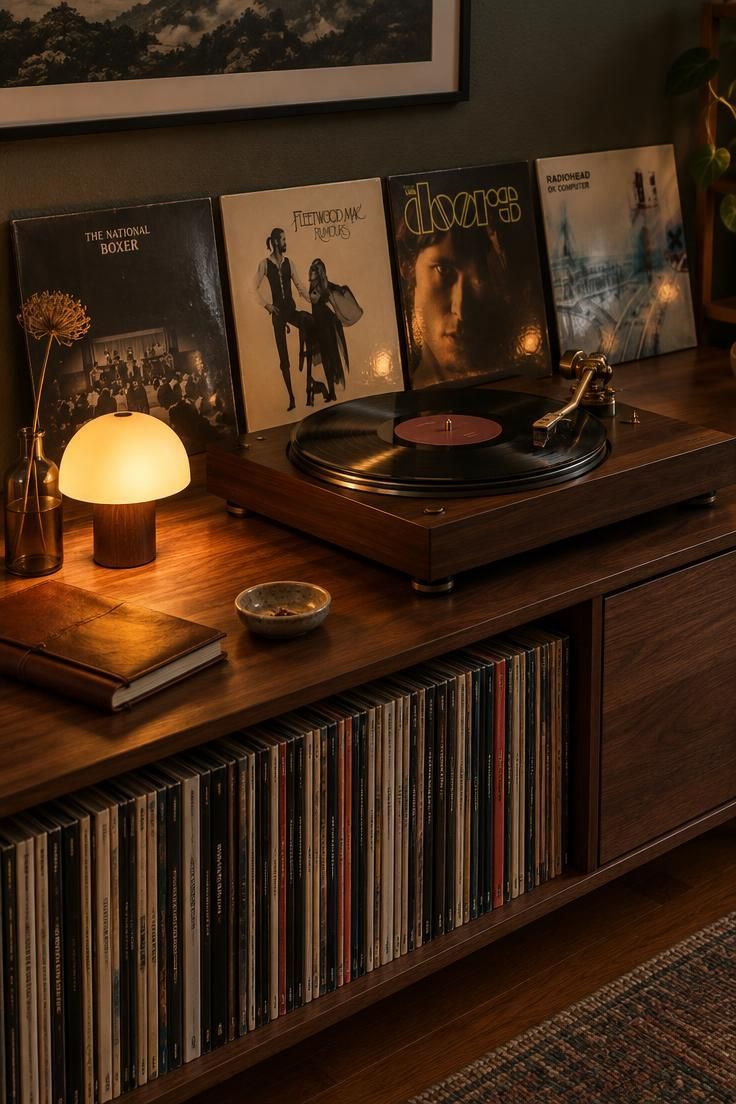 11 Moody Man Cave Ideas for a Warm, Layered Retreat 11 Turntable on a dark walnut console with a warm-glow lamp, face-out album covers, and a low shelf of records below.