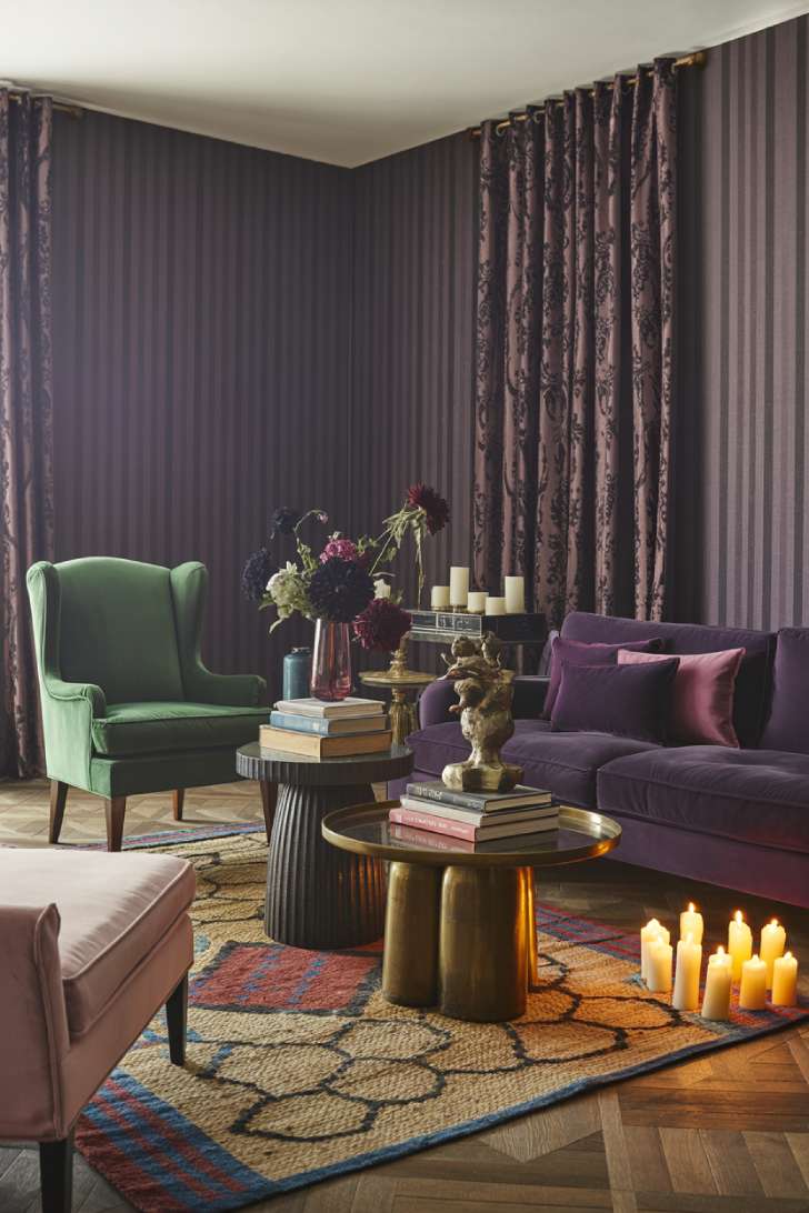 Dark plum and black striped wallpaper maximalist living room with velvet chaise lounge and dark florals