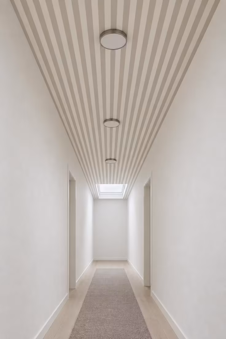 15 Narrow Hallway Ideas That Make Small Spaces Feel Grand 11 Fine cream and taupe stripes running lengthwise across a hallway ceiling with flush lights set into the pattern.