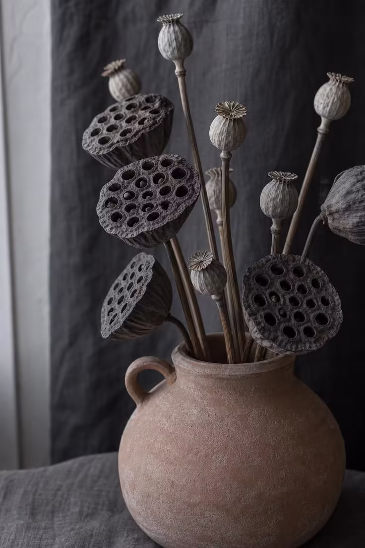11 Cozy Natural Fall Decor Ideas for a Warm, Calm Home 3 Dried lotus pods and poppy heads arranged in a squat clay jug for natural fall decor.