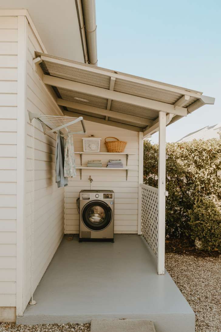 10 Creative Outdoor Laundry Room Ideas for Small Spaces 6 A lean-to laundry shelter attached to a white weatherboard home with a retractable clothesline, timber shelves, and a lattice privacy panel