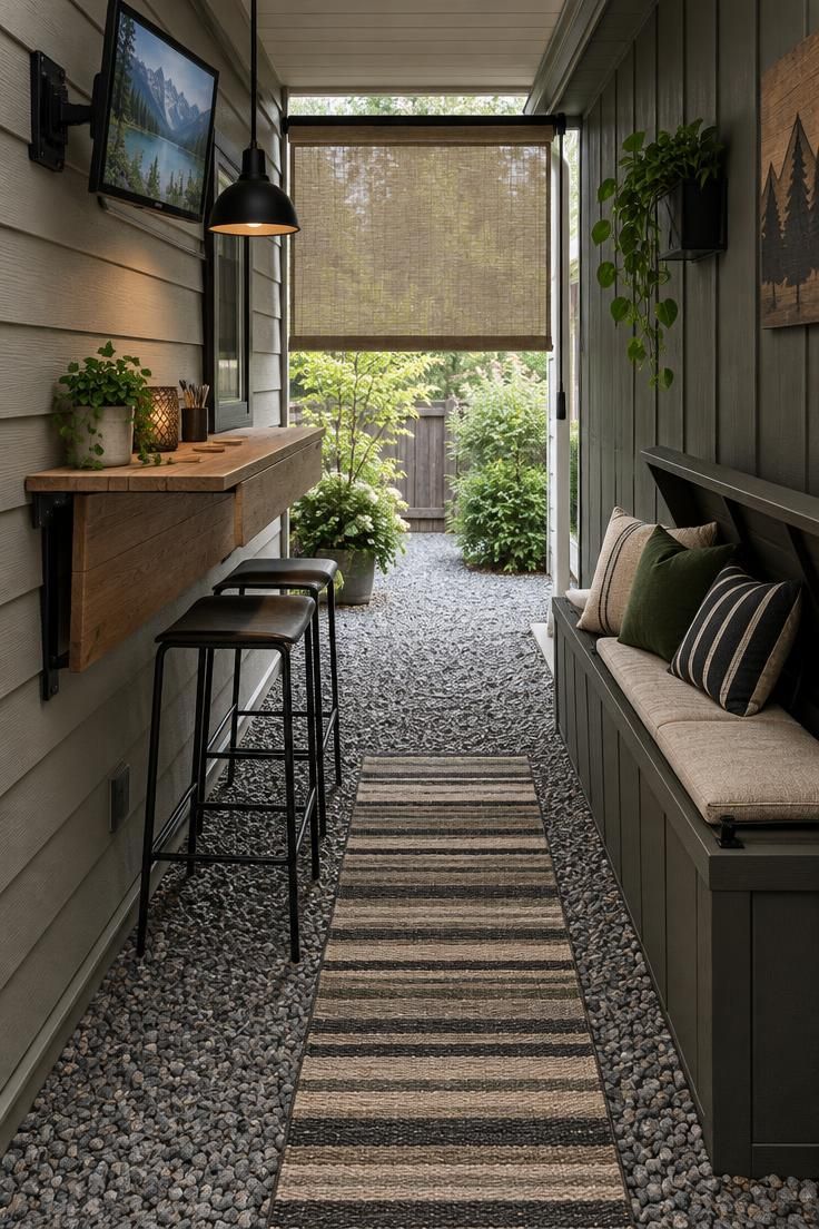 A narrow breezeway between house and garage, a fold-down wooden bar on the wall, a narrow bench with storage, a small TV on a swivel arm, and a pendant light.