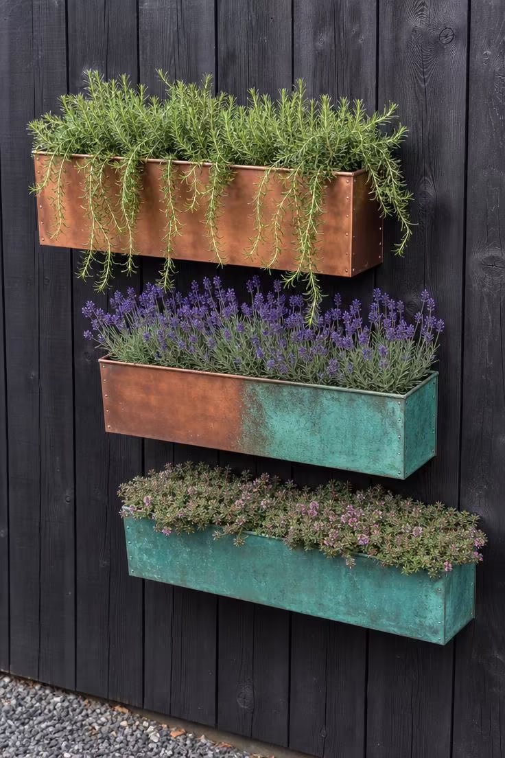 11 Striking Outdoor Wall Decor Ideas Worth Copying 6 Three copper wall planters with verdigris patina at staggered heights on a charcoal fence with trailing herbs