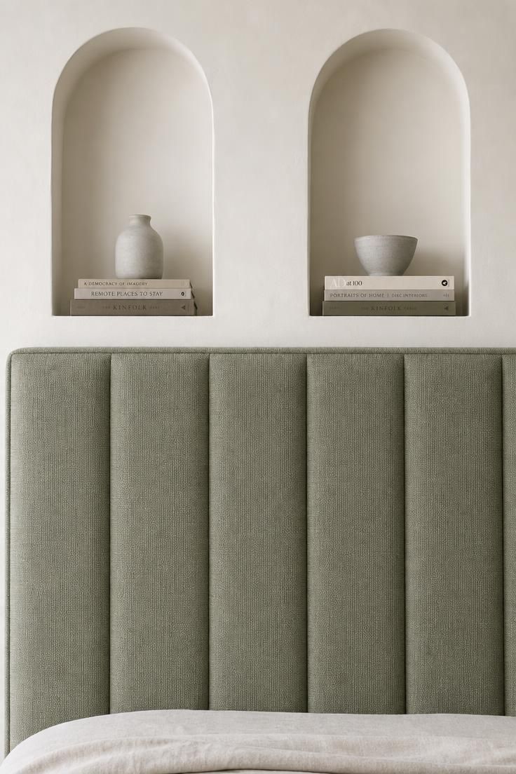 13 Cozy Over the Bed Storage Ideas for a Calm Bedroom 4 Sage green upholstered headboard with two recessed plaster niches above holding books and ceramic vessels.