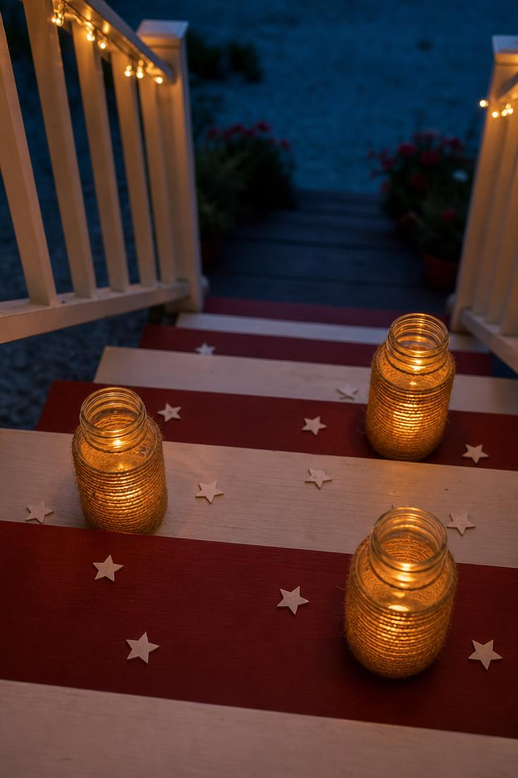 10 Bold Patriotic Front Porch Decor Ideas for Every Home 5 Overhead view of Mason jar lanterns with battery candles on red and white painted porch steps at twilight with scattered paper stars