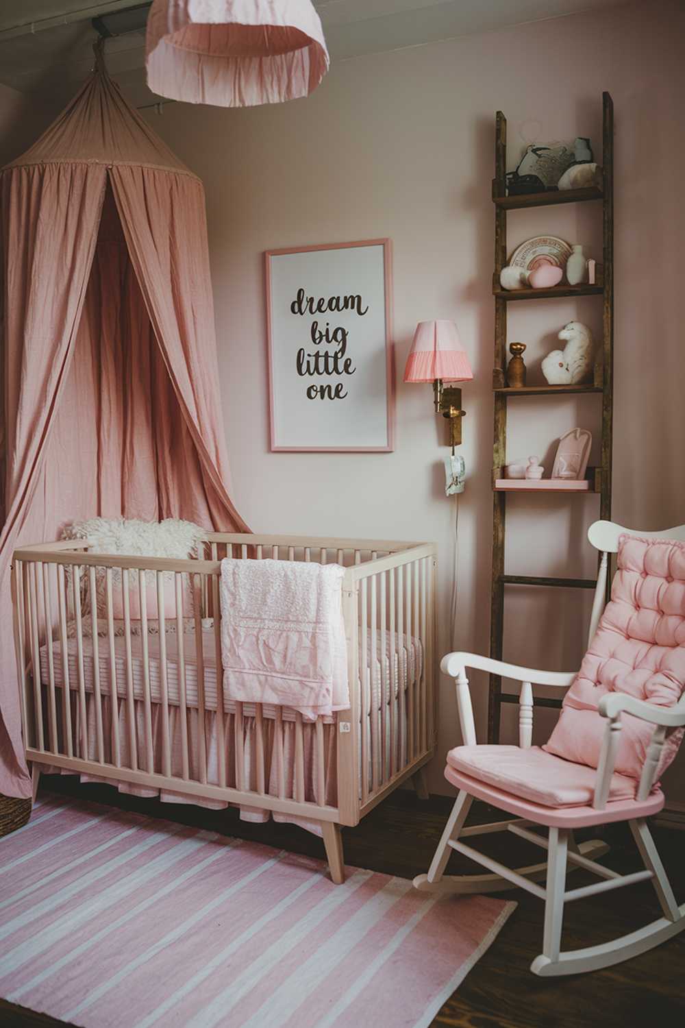 A pink boho nursery room decor. The room has a vintage feel with rustic elements. There's a crib with a pink and white striped bedding and a fluffy white pillow. Above the crib, there's a wooden crib bed canopy with pink and white fabric. On the wall, there's a framed art piece with the text "Dream big little one". The floor is covered with a pink and white striped rug. There's a wooden rocking chair with a white frame and pink seat cushion. On the wall, there's a wooden shelf with white and pink items. There's a lamp with a pink shade and a white base. The room has a vintage wooden ladder.